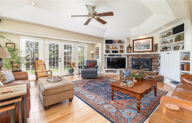 living area featuring a raised ceiling, healthy amount of natural light, ceiling fan, a fireplace, and recessed lighting