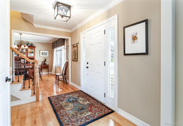foyer featuring a chandelier, crown molding, wood finished floors, baseboards, and stairs