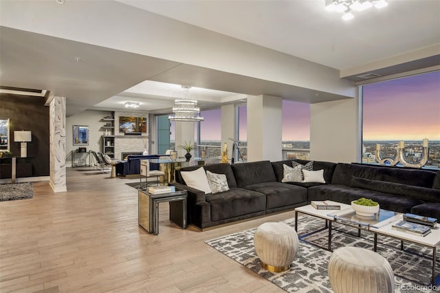 living room with a fireplace, light wood-style flooring, and a notable chandelier