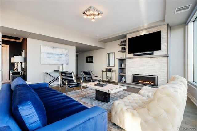 living area featuring visible vents, a fireplace, baseboards, and wood finished floors