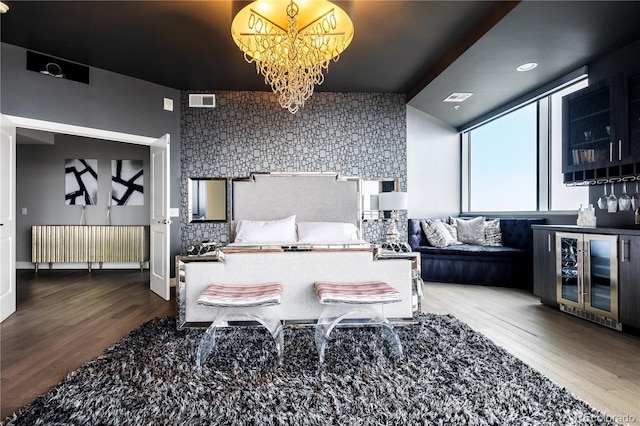 bedroom with a chandelier, an accent wall, a dry bar, and wood finished floors