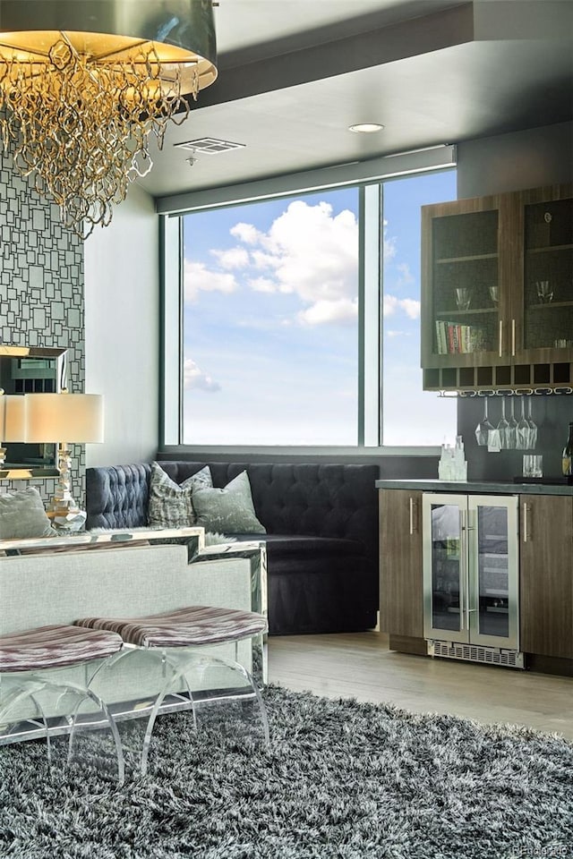 living area featuring a healthy amount of sunlight, wine cooler, a dry bar, and wood finished floors