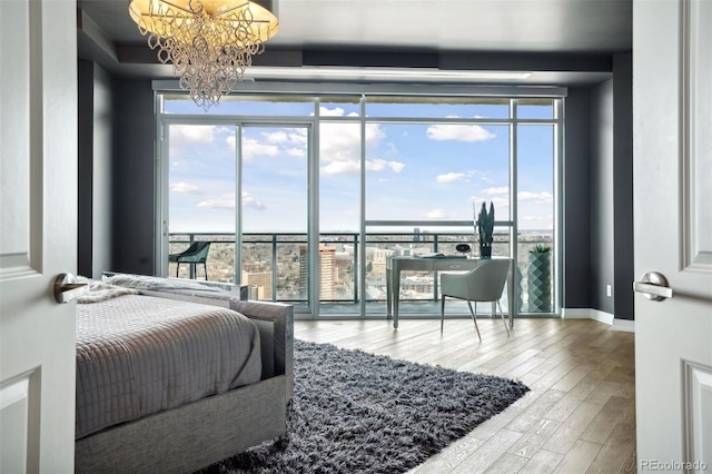 bedroom featuring access to exterior, a notable chandelier, wood finished floors, a wall of windows, and baseboards