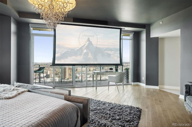 bedroom with a wall of windows, multiple windows, baseboards, and wood finished floors