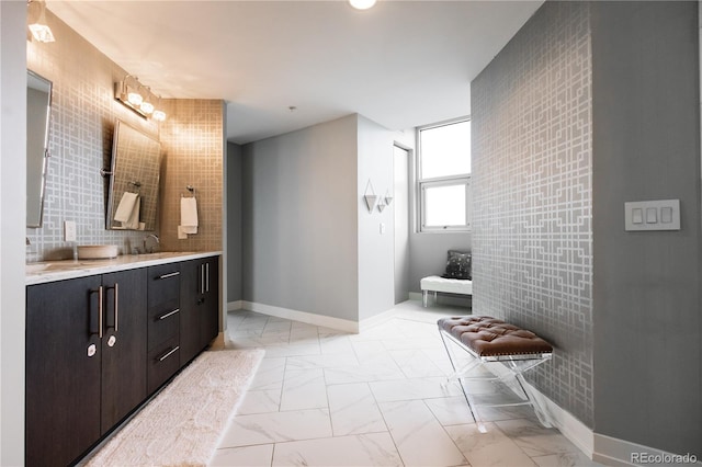 full bathroom featuring double vanity, marble finish floor, baseboards, and a sink