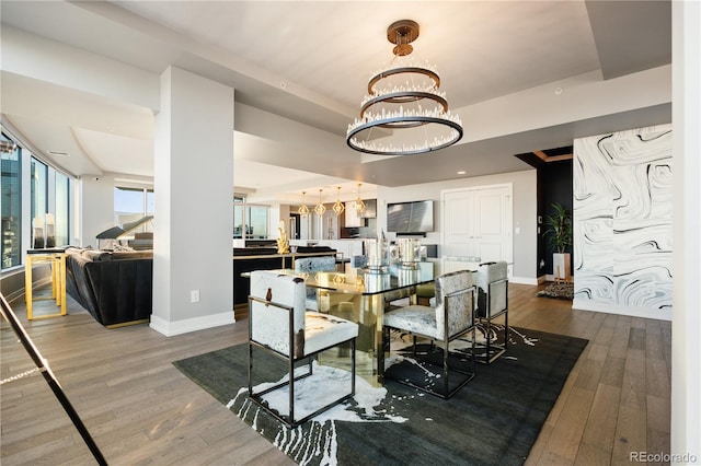 dining room with dark wood finished floors, a notable chandelier, and baseboards