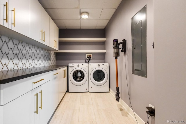 washroom with cabinet space, washing machine and dryer, electric panel, and baseboards