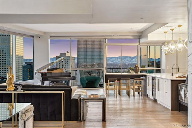 interior space featuring a mountain view, a city view, beverage cooler, a healthy amount of sunlight, and light wood-type flooring