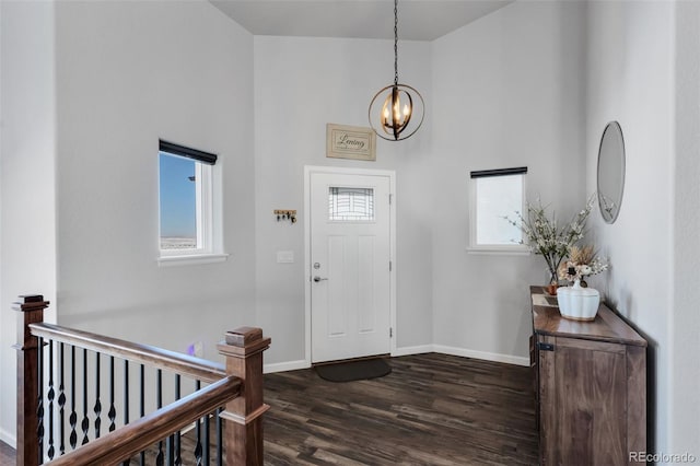 foyer entrance with dark wood-type flooring, a high ceiling, and a notable chandelier