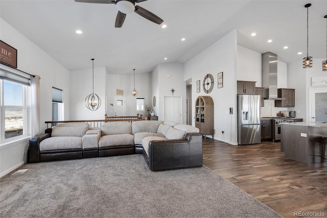 living room with dark hardwood / wood-style floors, ceiling fan with notable chandelier, and a towering ceiling