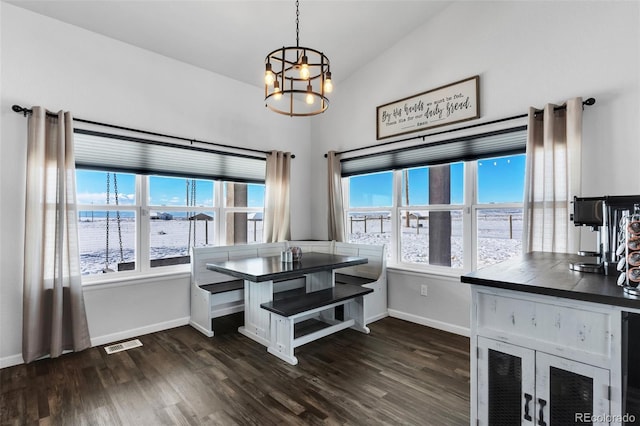 dining space featuring plenty of natural light, a notable chandelier, lofted ceiling, and a water view