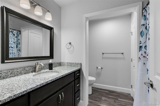 bathroom with toilet, hardwood / wood-style floors, and vanity