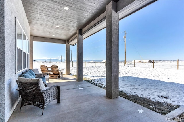 snow covered patio featuring an outdoor living space and a water view