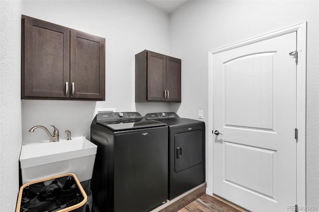 laundry area featuring separate washer and dryer, sink, dark hardwood / wood-style floors, and cabinets