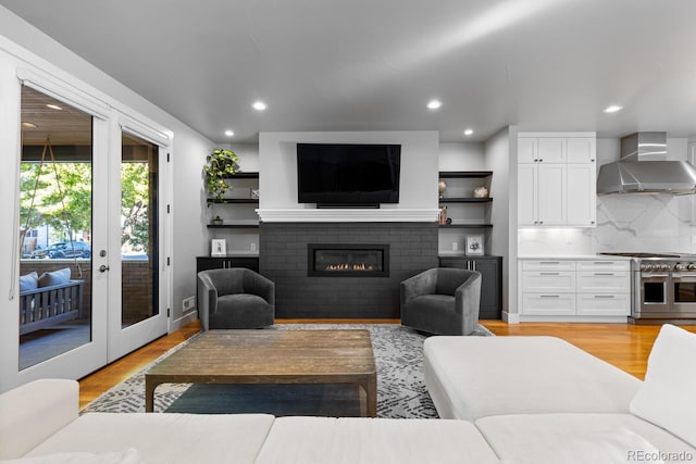 living room featuring french doors, light hardwood / wood-style floors, and a brick fireplace