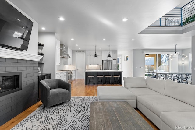 living room featuring a chandelier, light hardwood / wood-style floors, sink, and a brick fireplace