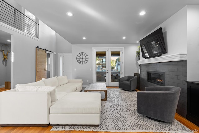 living room featuring a barn door, light hardwood / wood-style floors, and a brick fireplace