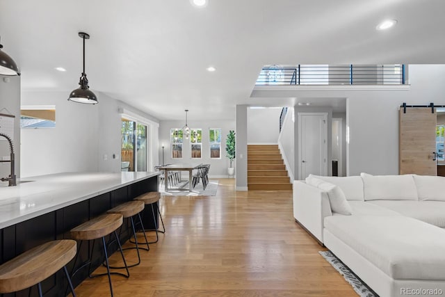 living room featuring a barn door, sink, and light hardwood / wood-style flooring