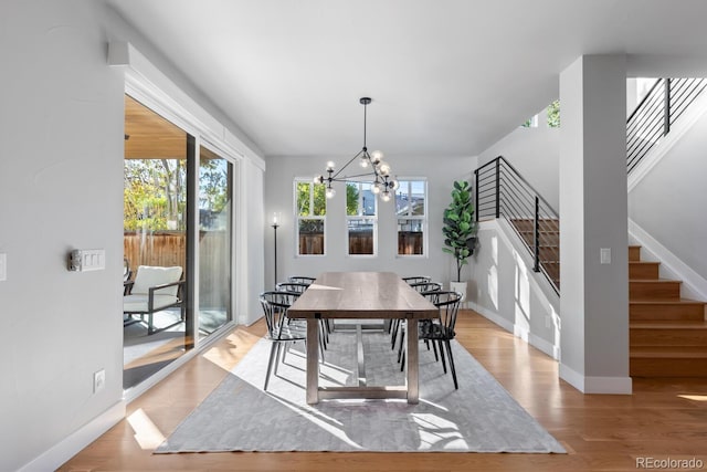 dining space featuring light wood-type flooring, a wealth of natural light, and an inviting chandelier