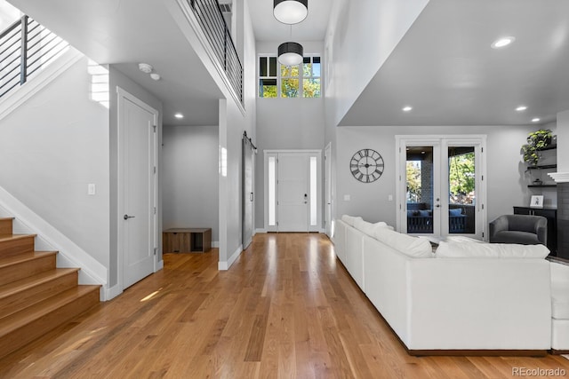 foyer with a towering ceiling, a barn door, light hardwood / wood-style floors, and a healthy amount of sunlight