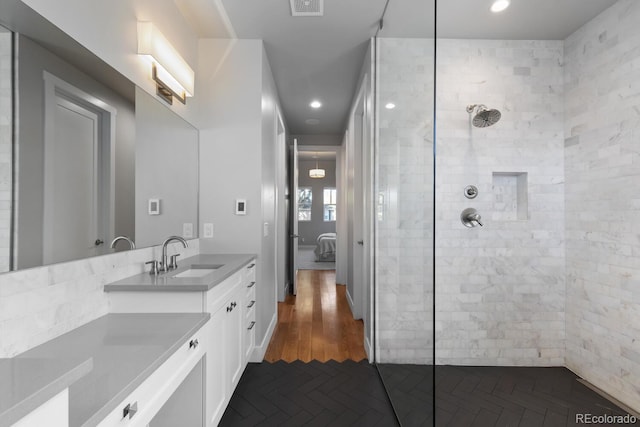 bathroom with a tile shower, vanity, and hardwood / wood-style flooring