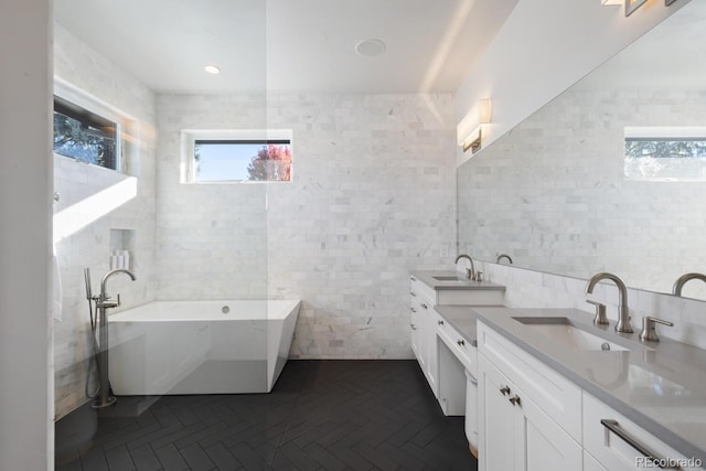 bathroom with vanity, a tub, and tile walls