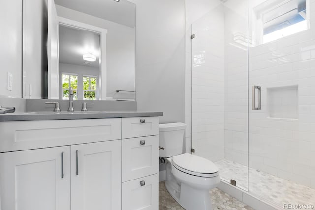 bathroom featuring a shower with door, vanity, and toilet