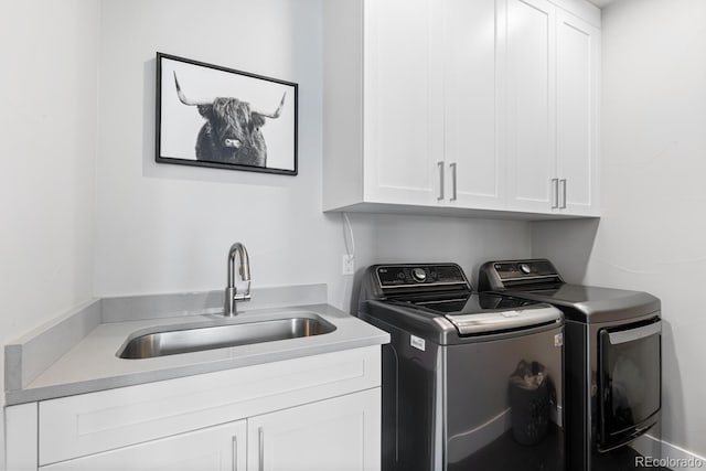 clothes washing area featuring cabinets, sink, and washing machine and clothes dryer