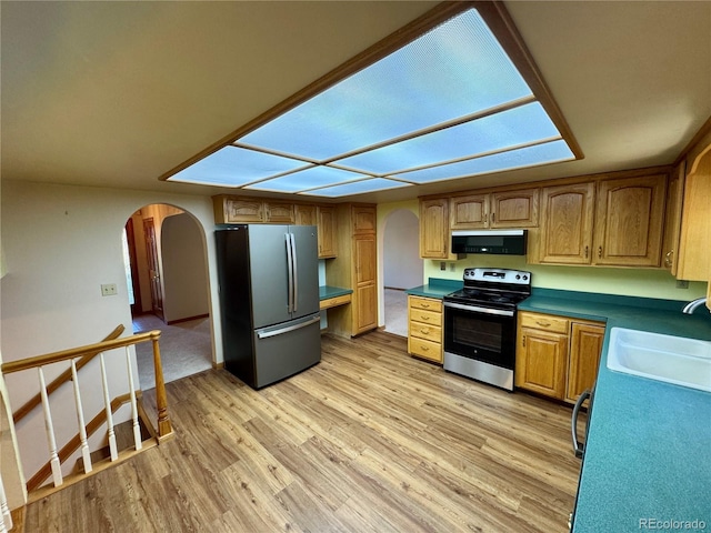 280 Raven Hills Rd, Colorado Springs, CO 80919 - kitchen with stainless steel appliances, arched walkways, a sink, and light wood finished floors