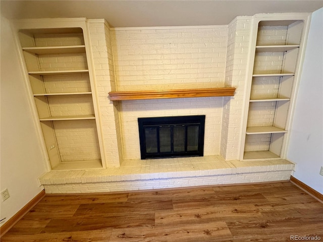 280 Raven Hills Rd, Colorado Springs, CO 80919 - unfurnished living room with built in shelves, baseboards, a fireplace, and wood finished floors