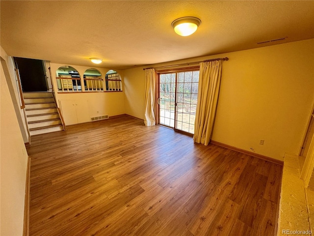 280 Raven Hills Rd, Colorado Springs, CO 80919 - empty room featuring a textured ceiling, stairs, baseboards, wood finished floors, and visible vents