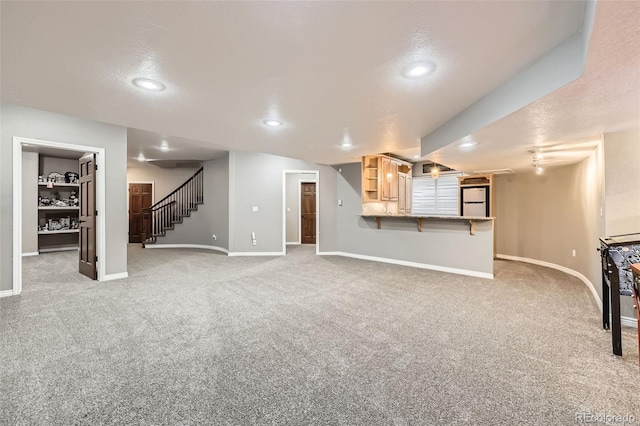 unfurnished living room featuring stairway, baseboards, and light colored carpet
