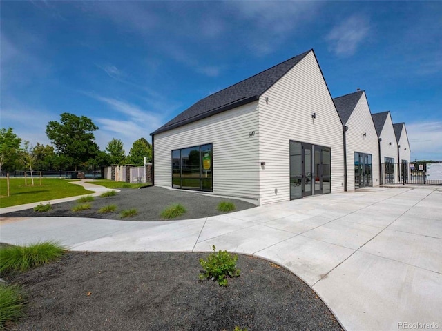 view of side of property featuring fence, a patio, and driveway