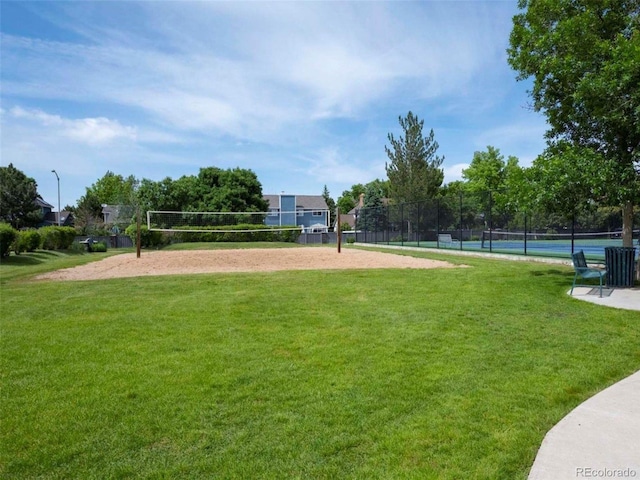 view of community with a yard, a tennis court, fence, and volleyball court