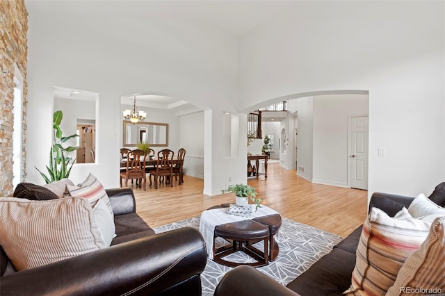 9468 E Aspen Hill Ln, Lone Tree, CO 80124 - living room with arched walkways, a high ceiling, a chandelier, and light wood-type flooring