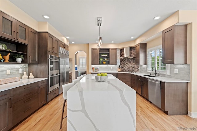 9468 E Aspen Hill Ln, Lone Tree, CO 80124 - kitchen with open shelves, appliances with stainless steel finishes, wall chimney exhaust hood, arched walkways, and wine cooler
