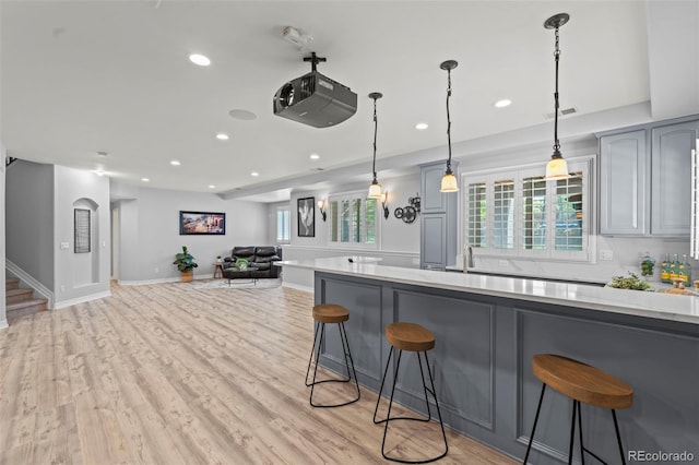 9468 E Aspen Hill Ln, Lone Tree, CO 80124 - kitchen featuring a breakfast bar area, gray cabinetry, recessed lighting, decorative light fixtures, and light stone counters