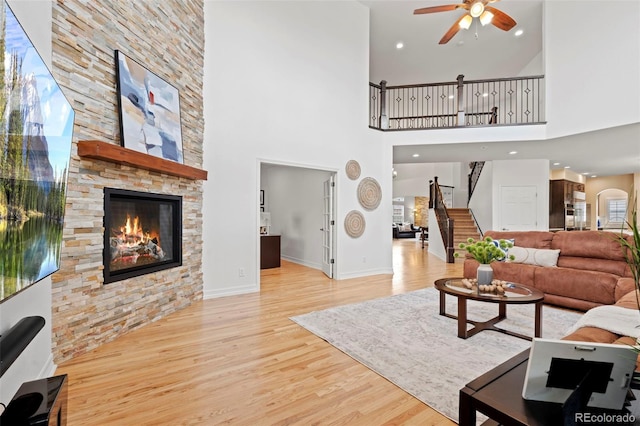 9468 E Aspen Hill Ln, Lone Tree, CO 80124 - living area featuring a ceiling fan, stairs, a fireplace, wood finished floors, and a high ceiling