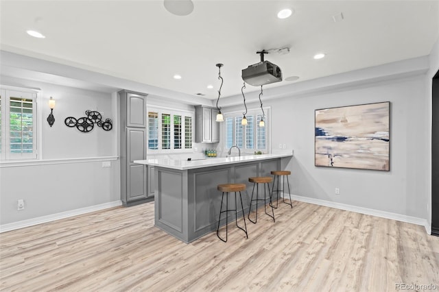 9468 E Aspen Hill Ln, Lone Tree, CO 80124 - kitchen with gray cabinets, a kitchen breakfast bar, light wood-type flooring, a peninsula, and recessed lighting