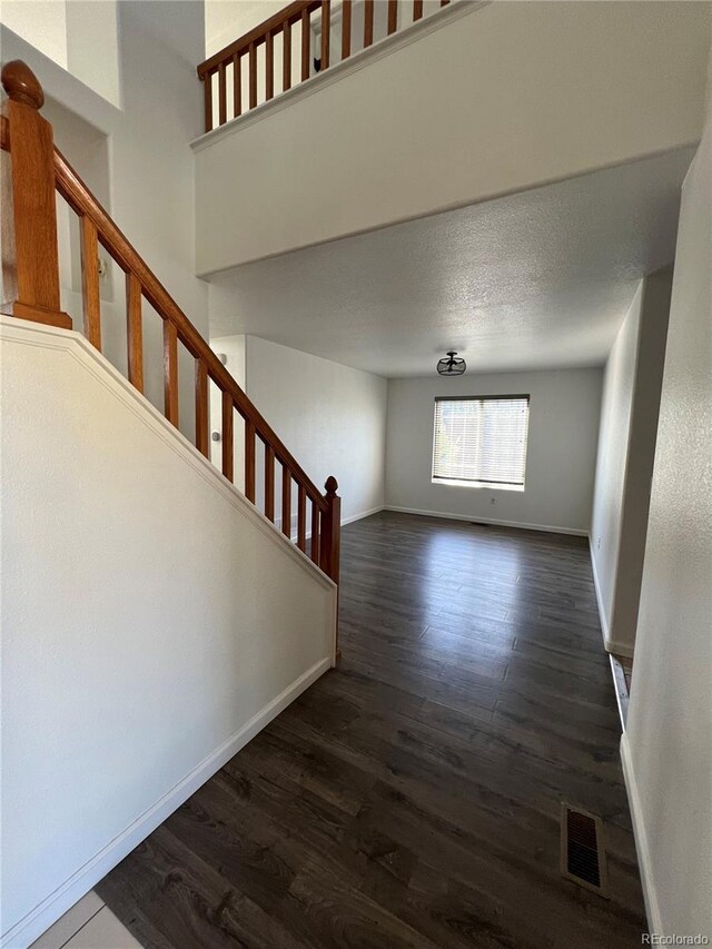 2604 S Dunkirk Ct, Aurora, CO 80013 - spare room with baseboards, dark wood-style floors, visible vents, and stairway