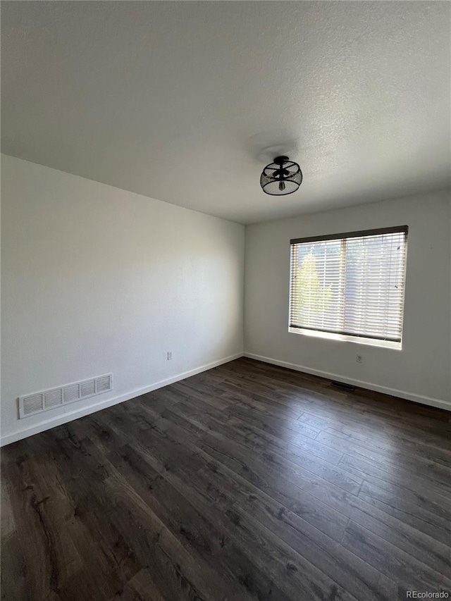 empty room with a textured ceiling and dark hardwood / wood-style floors