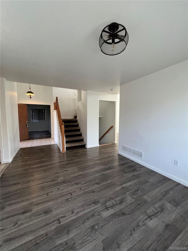 2604 S Dunkirk Ct, Aurora, CO 80013 - unfurnished living room featuring stairs, dark wood-type flooring, visible vents, and baseboards