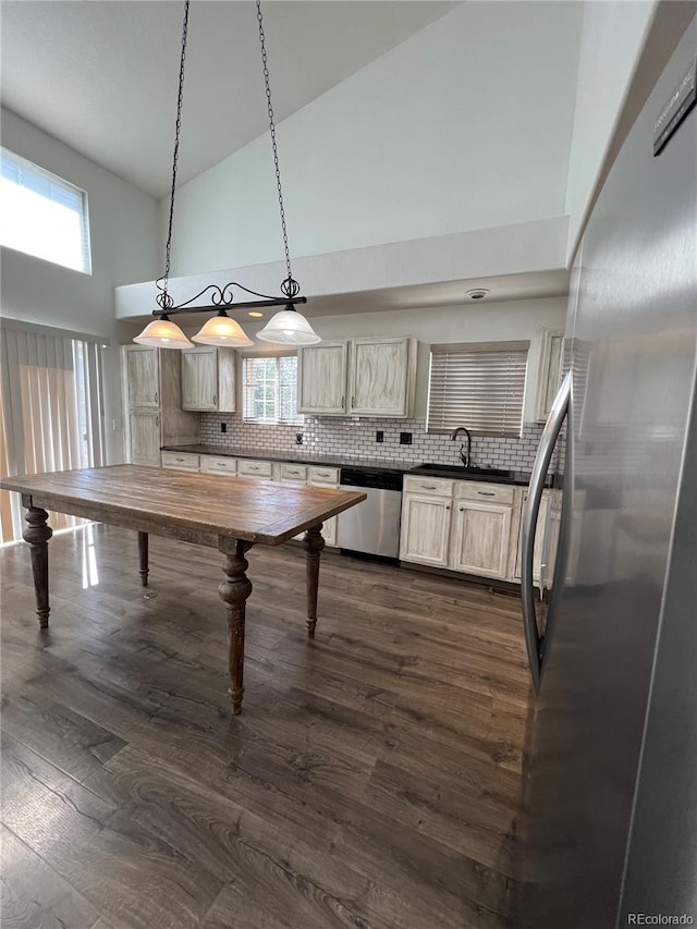 kitchen with appliances with stainless steel finishes, hanging light fixtures, a wealth of natural light, and high vaulted ceiling