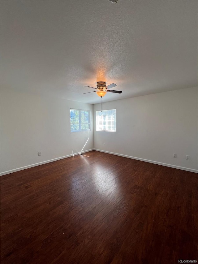 empty room with ceiling fan, a textured ceiling, and dark wood-type flooring