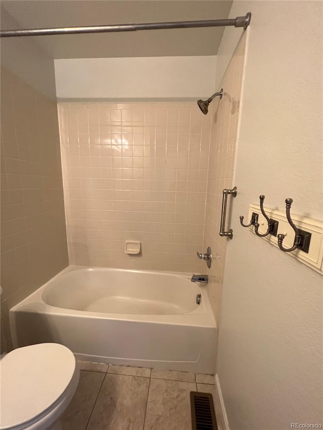 bathroom featuring tiled shower / bath combo, toilet, and tile patterned floors