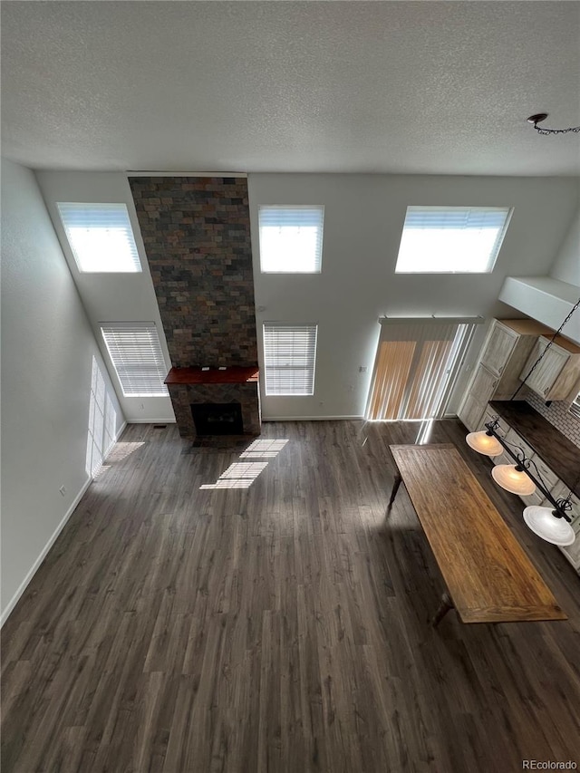 2604 S Dunkirk Ct, Aurora, CO 80013 - unfurnished living room featuring a stone fireplace, a textured ceiling, baseboards, and wood finished floors
