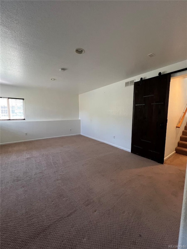 2604 S Dunkirk Ct, Aurora, CO 80013 - carpeted spare room featuring visible vents, baseboards, a barn door, a textured ceiling, and stairs