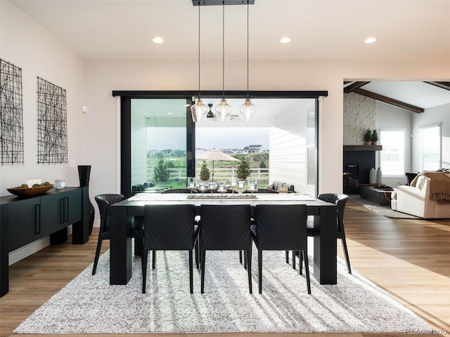 dining room with light wood-style flooring, recessed lighting, a fireplace, and lofted ceiling with beams