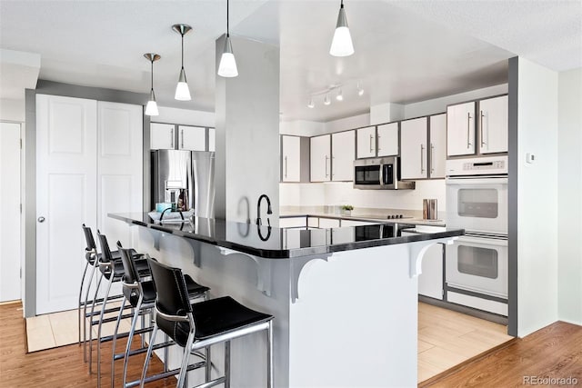 3131 E Alameda Ave Unit 803, Denver, CO 80209 - kitchen featuring stainless steel appliances, dark countertops, a breakfast bar area, and light wood-style floors