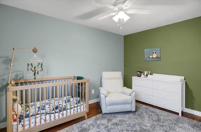1010 Vondelpark Dr, Colorado Springs, CO 80907 - bedroom featuring a nursery area, wood finished floors, ceiling fan, and a textured ceiling